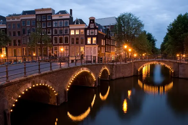 Canal bridges and canal houses reflected in Amsterdam at dusk